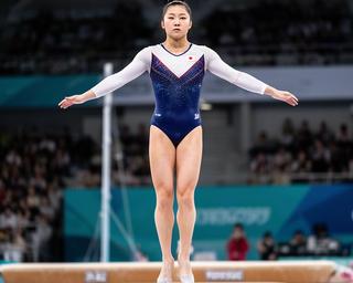 演技台で着地を決める日本人女子体操選手、明るい国際大会会場